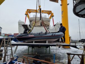 Ein Kran hebt das Suzumar Schlauchboot zur Passprobe auf die neuen, maßgefertigten Keile auf der Badeplattform.